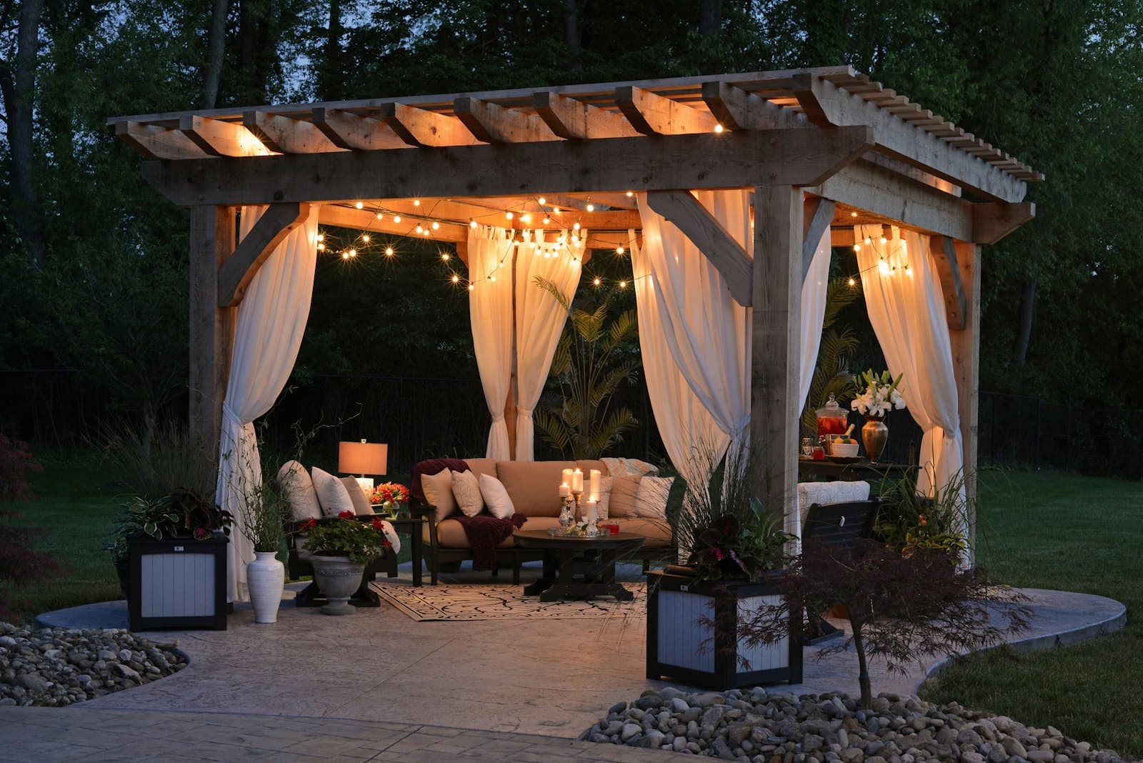 Pergola with curtains and string lights at dusk