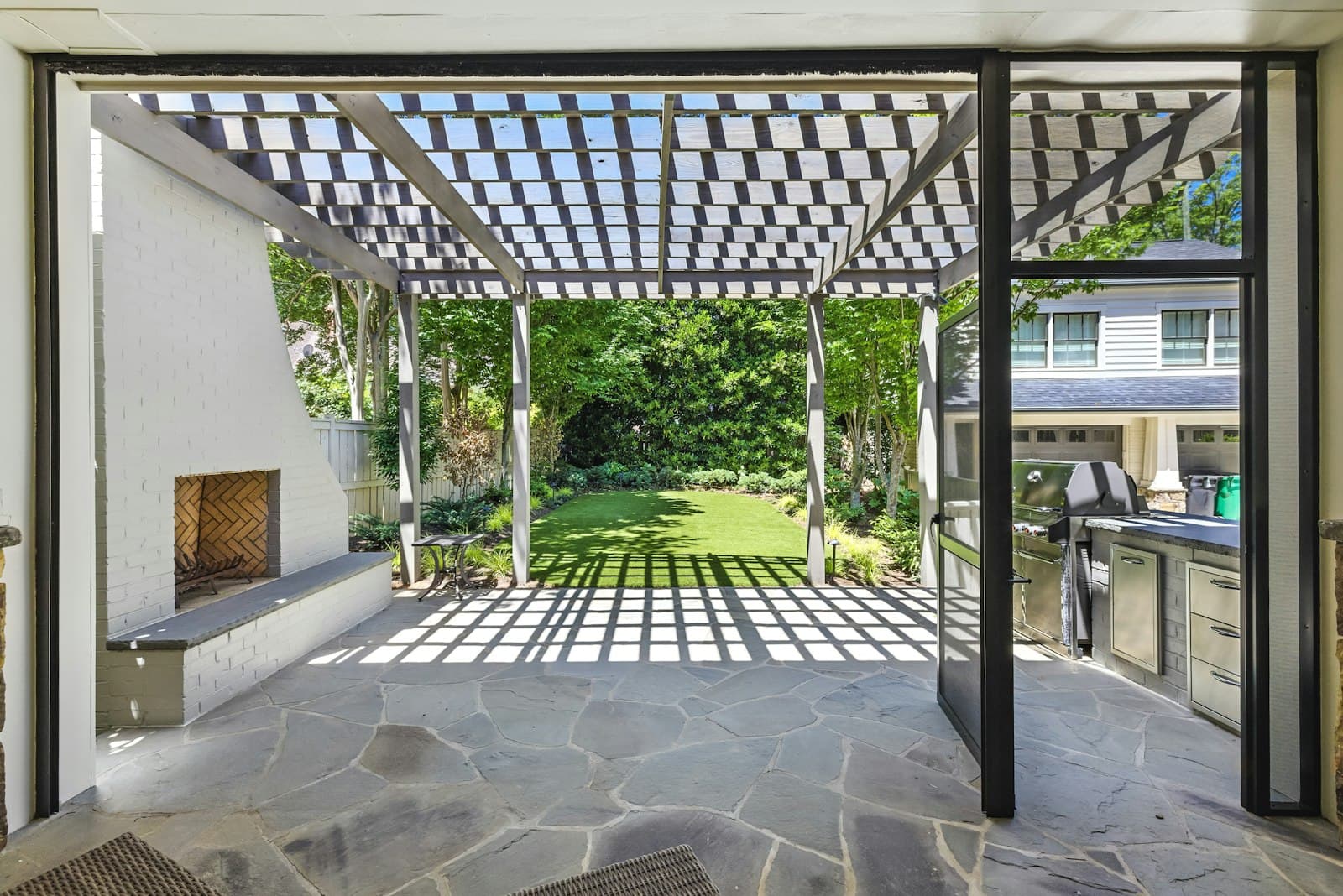 Modern lattice pergola over a flagstone patio with outdoor kitchen