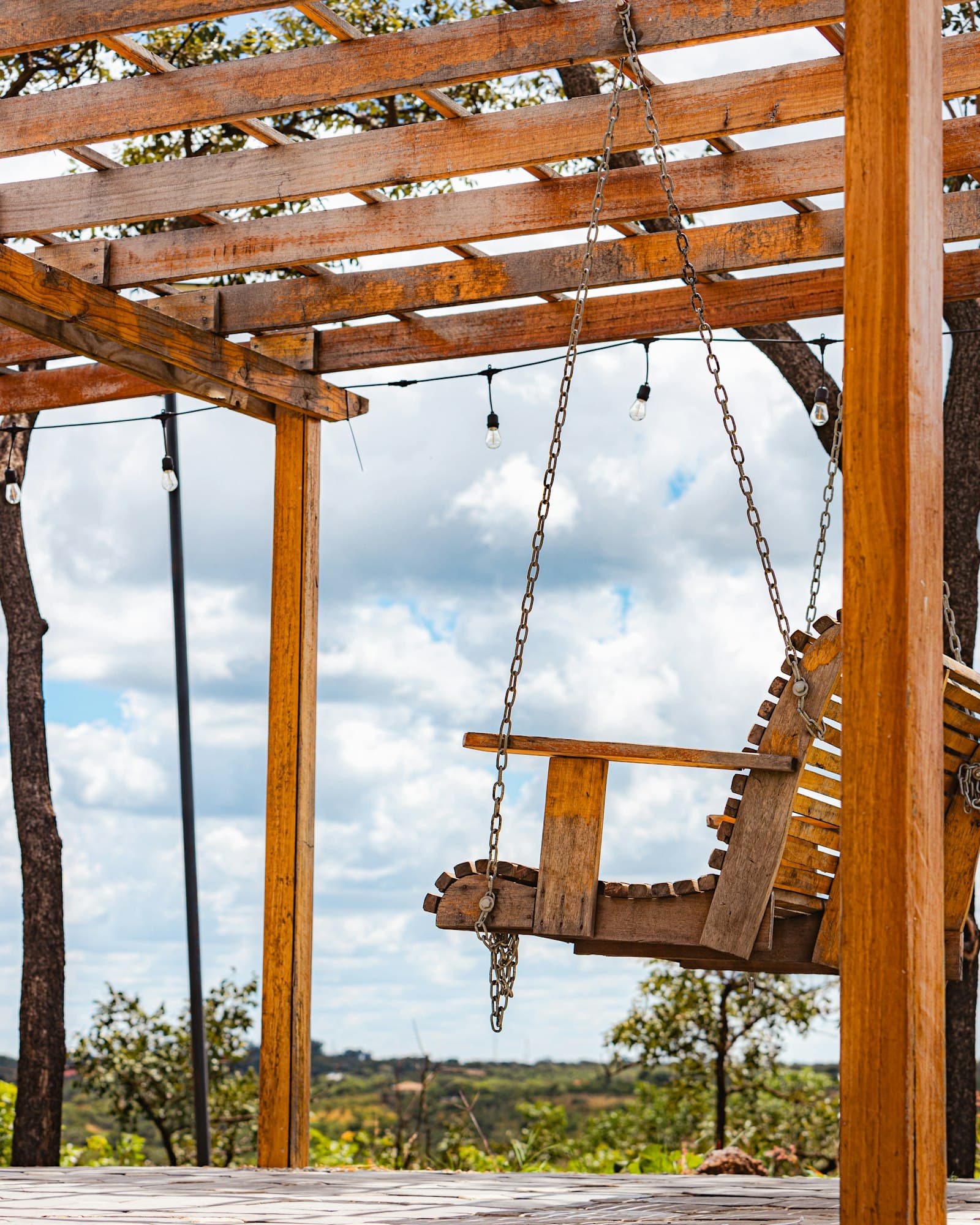Wooden swing hanging under a backyard pergola